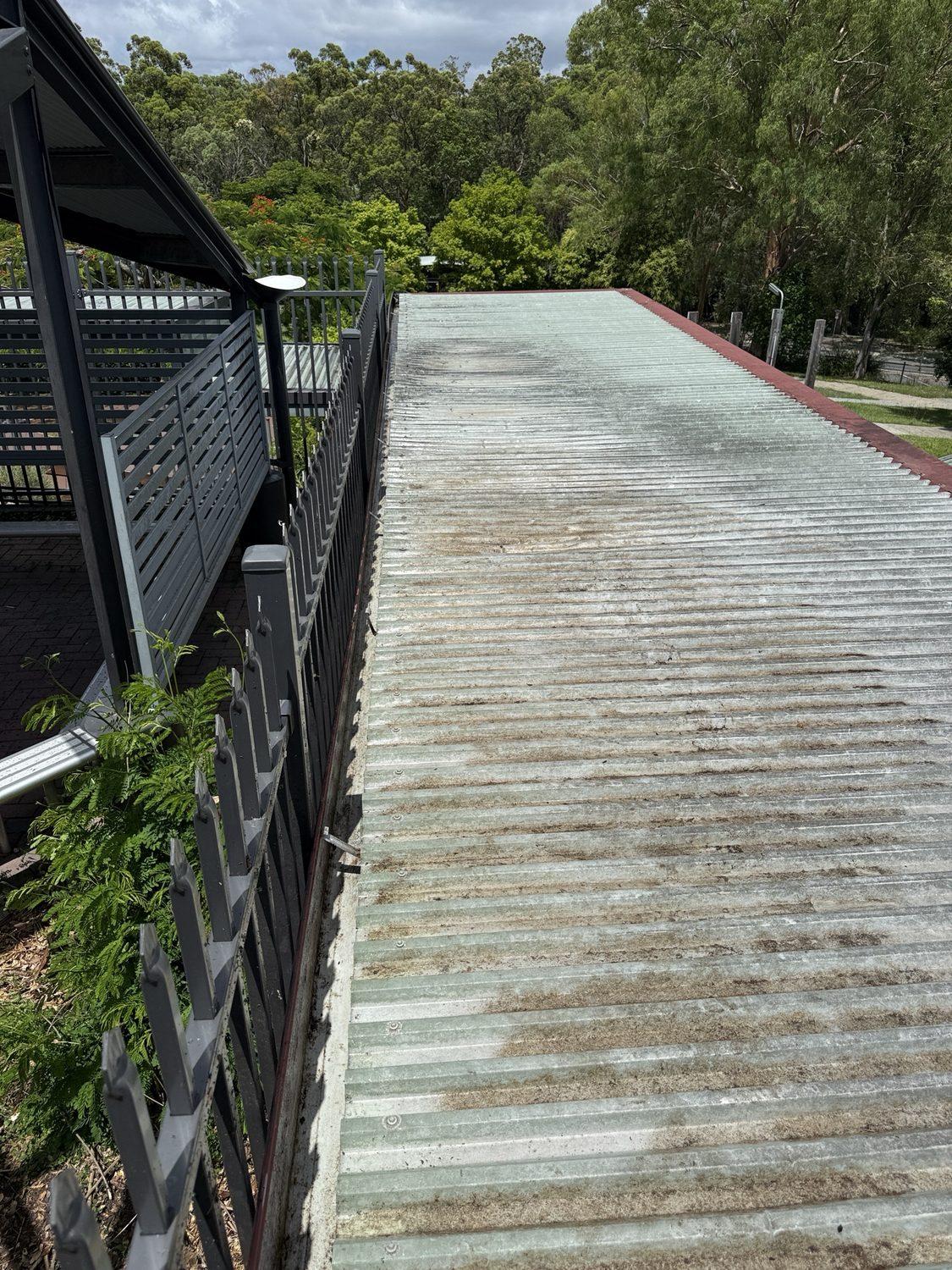 Large commercial metal roof with a long stained gutter line
